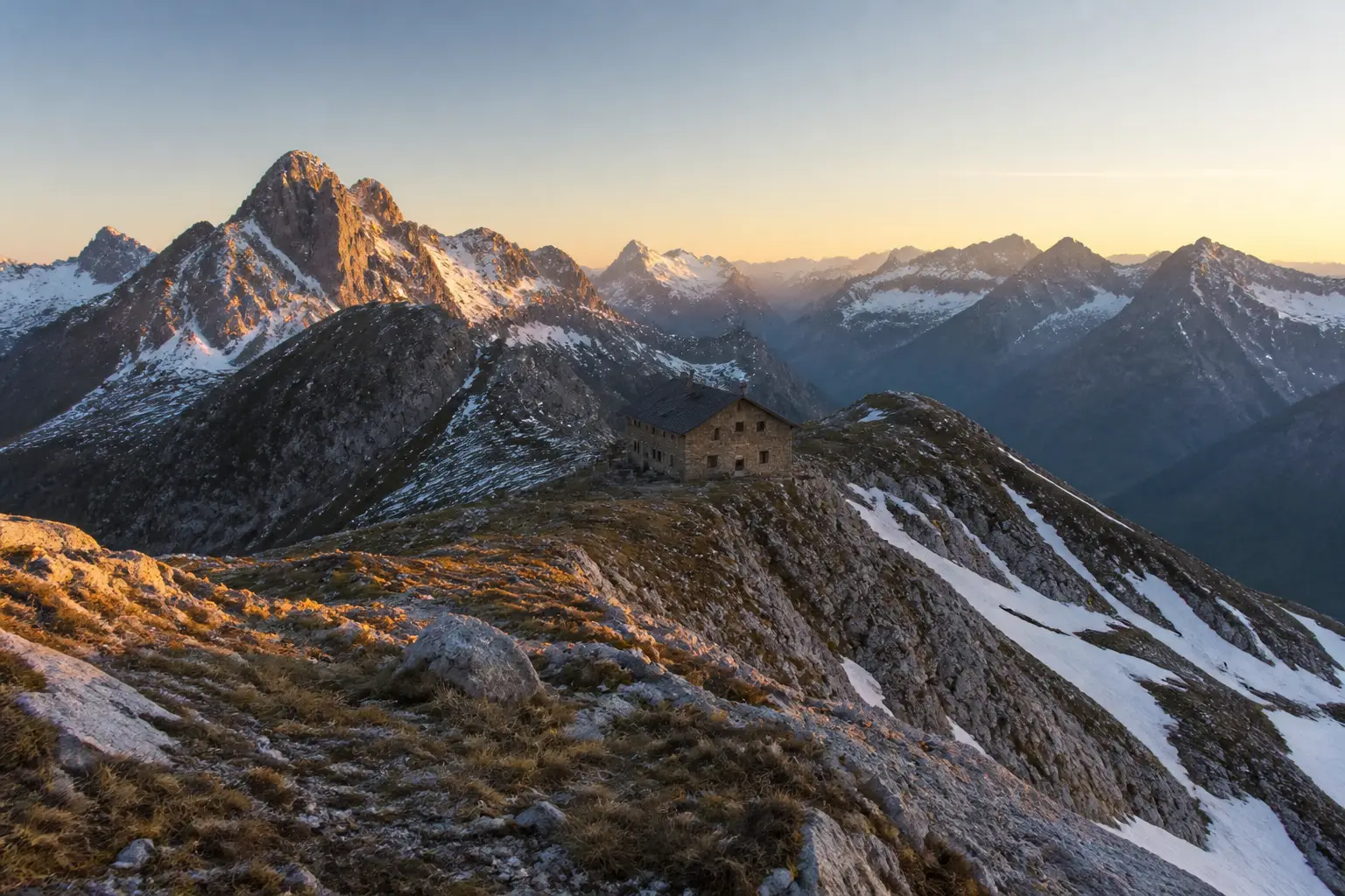 Alpine Berghütte auf einem Grat im Sonnenaufgang, typisch für die DACH-Alpen