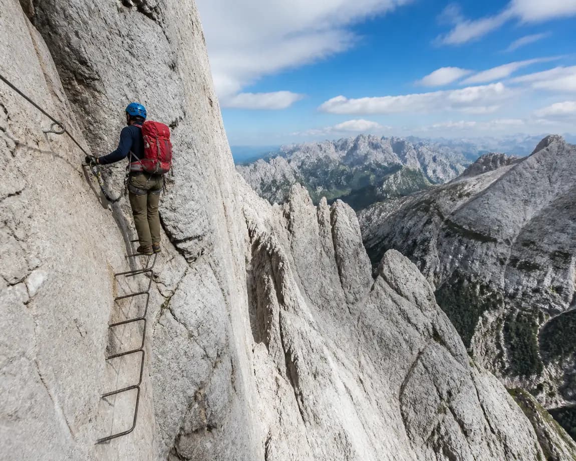 Klettersteiggeher an einer Leiterpassage vor den hellen Kalkgraten des Karwendelgebirges